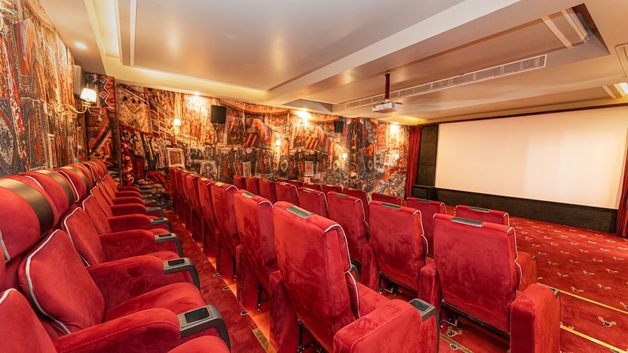 A movie theatre with red coloured comfortable chairs placed in front of a large screen - The Manor Luxury Hotel, Shimla
