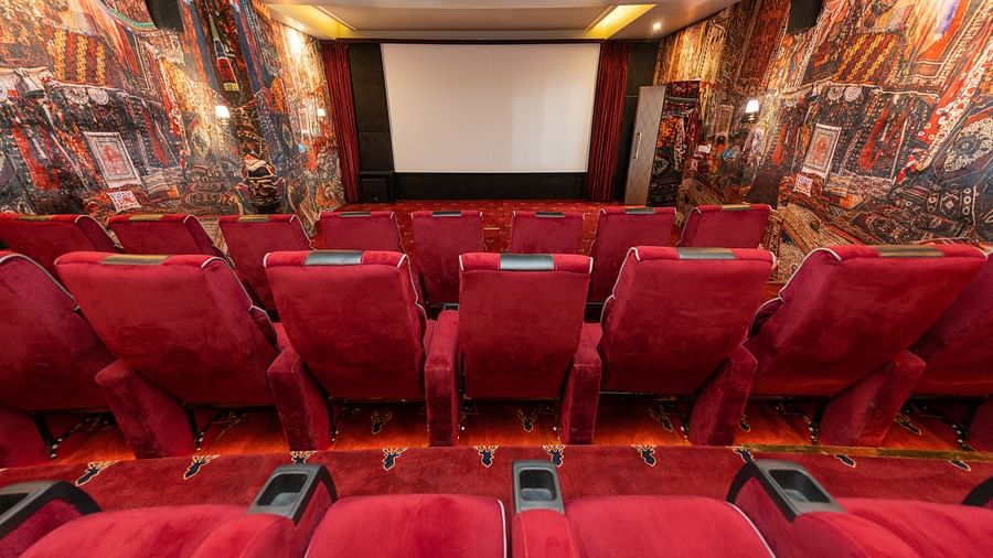 Rows of plush red seats in an ornately decorated cinema with walls draped in patterned rugs
