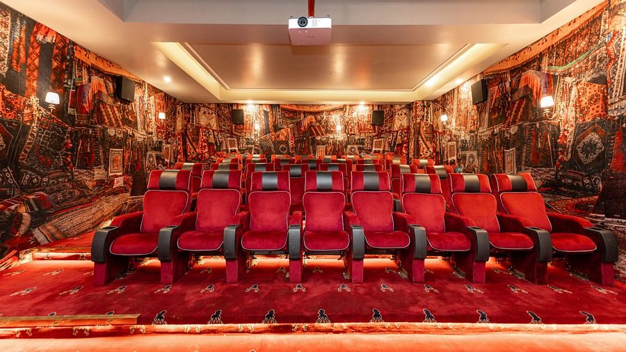 Another angles of rows of plush red seats in an ornately decorated cinema with walls draped in patterned rugs