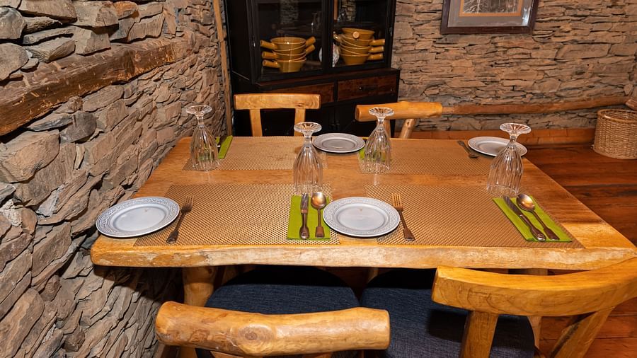 A close up shot of a wooden table with plates placed on it - The Manor Luxury Hotel, Shimla