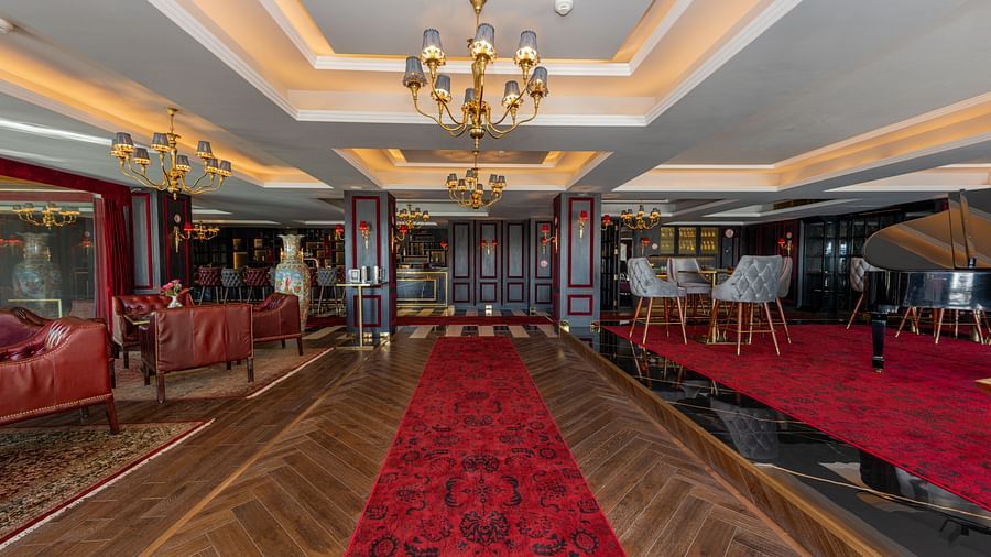 A long shot of the restaurant with a red carpet in the front and comfortable seating arrangement on either side of the carpet - The Manor Luxury Hotel, Shimla