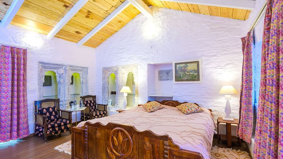 A double bed with side tables and lamps inside one of the rooms - Ramgarh Bungalows, Nainital.
