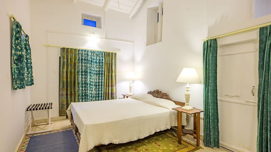 A double bed, side table and lamps inside one of the rooms - Ramgarh Bungalows, Nainital.