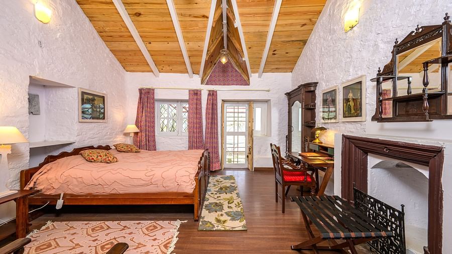 A double bed, a work desk, lamps in view inside one of the rooms - Ramgarh Bungalows, Nainital.