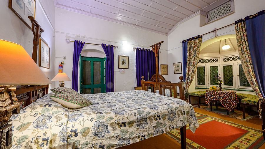 Luxurious king size bed at the bird room with curtains and window overlooking the mountains - Ramgarh Bungalows, Nainital.