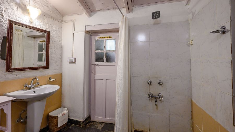 Bathroom of bird room with white walls and separate shower space and a washbasin with mirror - Ramgarh Bungalows, Nainital.