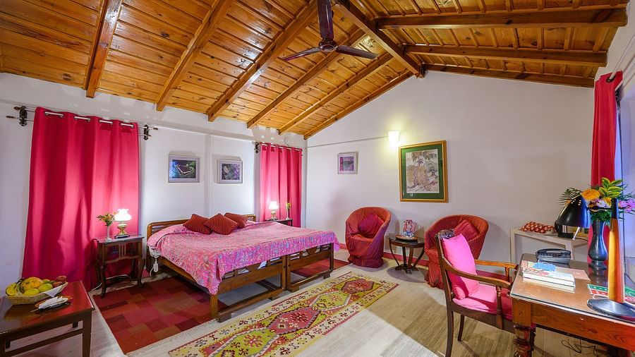 Fucia Room with wooden ceiling featuring a work desk and a grand bed - Ramgarh Bungalows, Nainital.