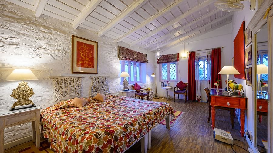 Gitonde room with stone carved walls and 2 queen size beds and a bedside lamp - Ramgarh Bungalows, Nainital.