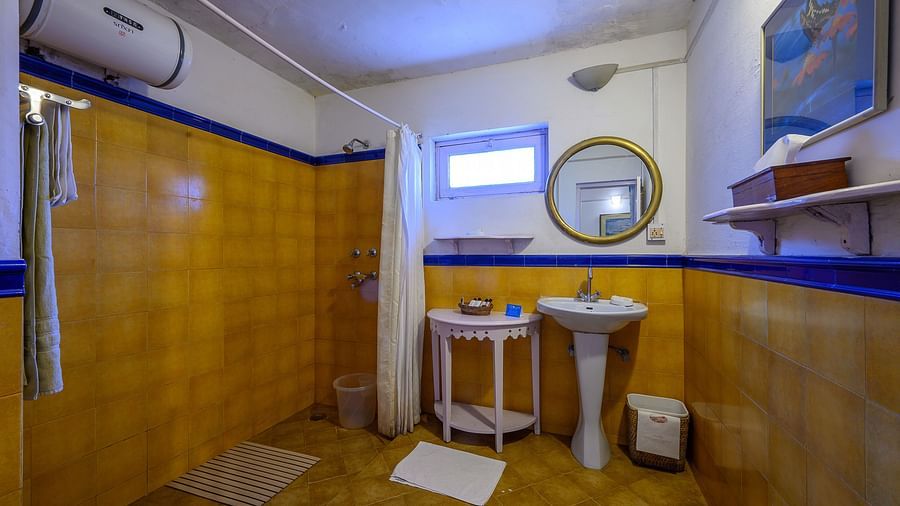 Irish room's bathroom with water heater, toiletries, a shower space and wash basin - Ramgarh Bungalows, Nainital.
