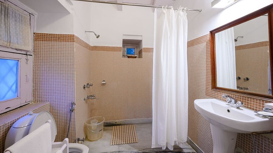 A spacious bathroom with shower area, washbasin and a large mirror - Ramgarh Bungalows, Nainital.