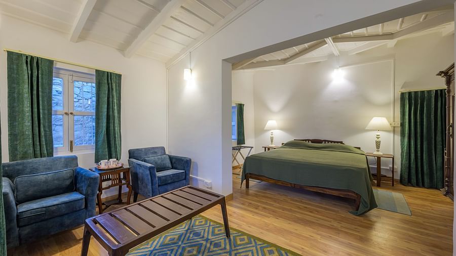 An overview of a room with a double bed, chairs and a coffee table - Ramgarh Bungalows, Nainital.