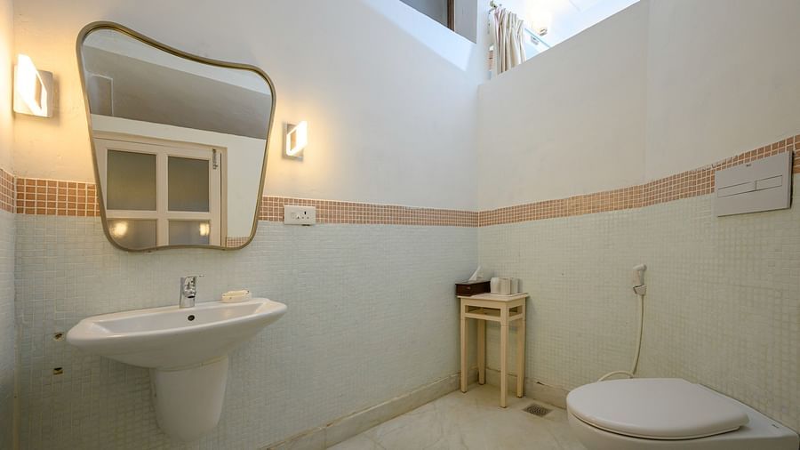Bathroom with sink, mirror, wall lighting, small table, toilet, and tiled floor - Tijara Fort-Palace - 19th Century, Alwar.
