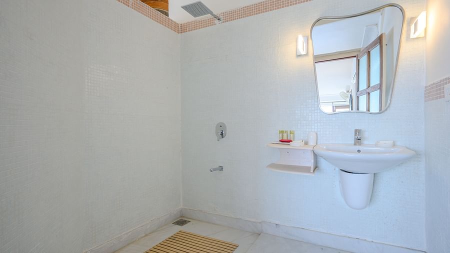 Bathroom with sink, mirror, wall lighting, shower area, floor mat, and tiled floor - Tijara Fort-Palace - 19th Century, Alwar.