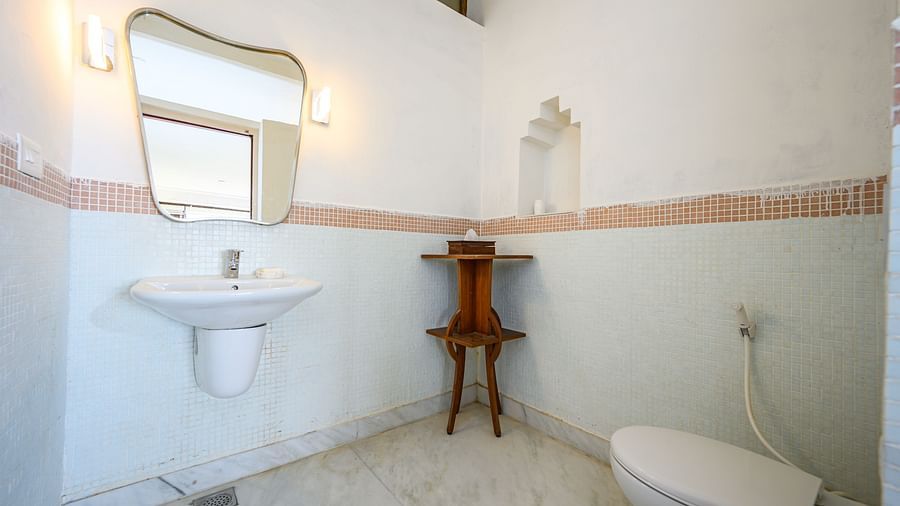 Bathroom with sink, mirror, wall lighting, small wooden table, toilet, and tiled floor - Tijara Fort-Palace - 19th Century, Alwar.