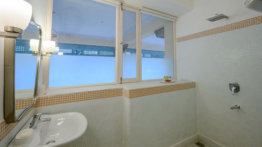 Bathroom with sink, mirror, wall lighting, windows, shower area, and tiled walls - Tijara Fort-Palace - 19th Century, Alwar.