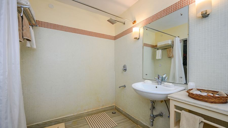 Bathroom with sink, mirror, wall lighting, shower curtain, towel racks, floor mat, and storage unit - Tijara Fort-Palace - 19th Century, Alwar.