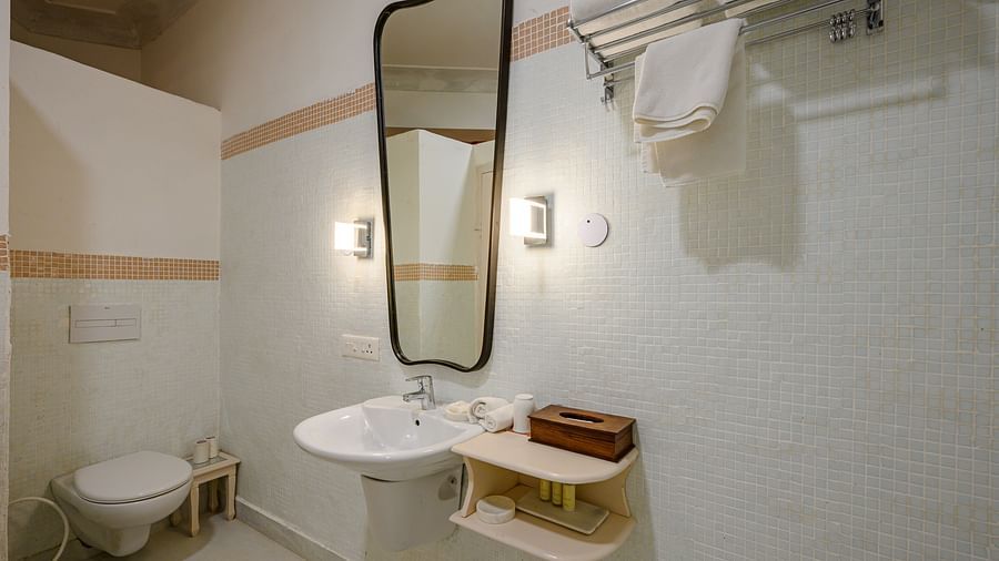 Bathroom with sink, mirror, wall lighting, toilet, towel rack, and storage shelves - Tijara Fort-Palace - 19th Century, Alwar.