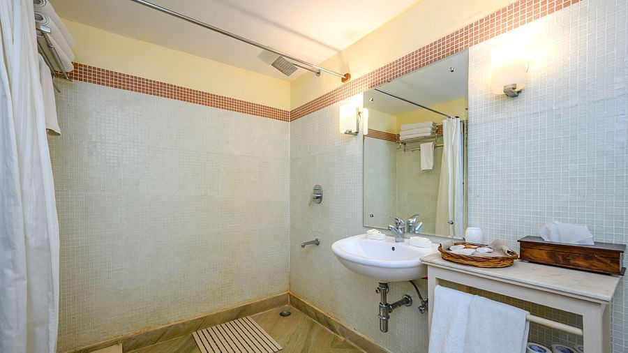 Bathroom with sink, mirror, wall lighting, shower curtain, floor mat, and storage unit - Tijara Fort-Palace - 19th Century, Alwar.