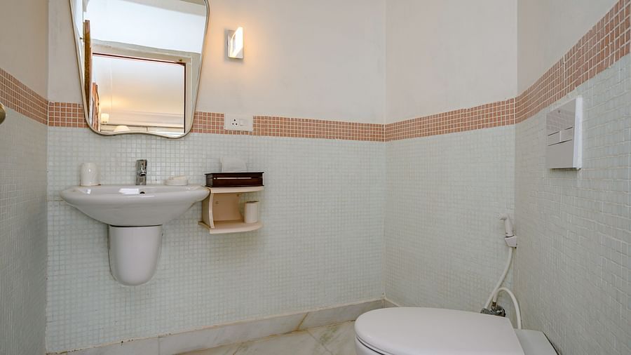 A bathroom with a toilet and a wall-mounted sink with a mirror above it at Tijara Fort-Palace - 19th Century, Alwar.