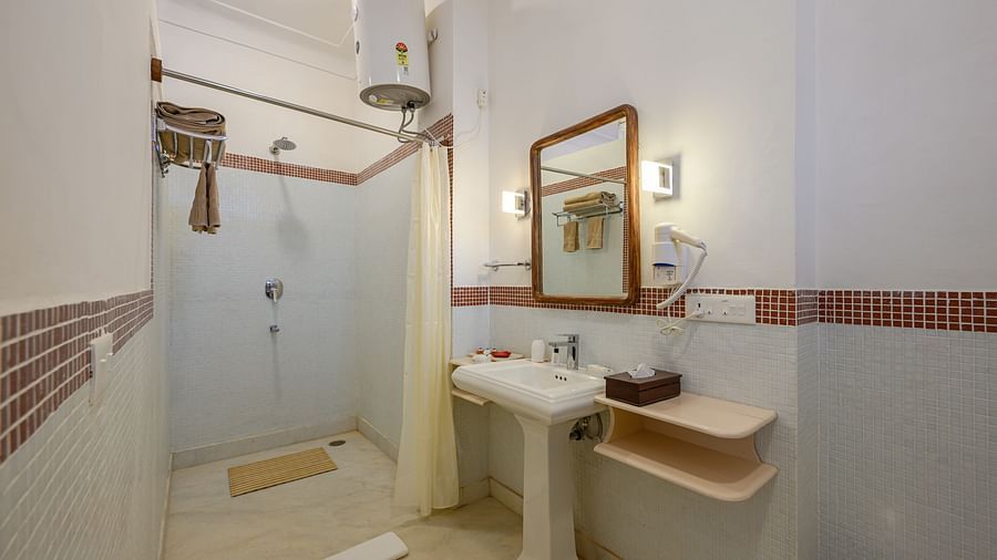 Bathroom with sink, mirror, shower curtain, water heater, and storage shelves - Tijara Fort-Palace - 19th Century, Alwar.