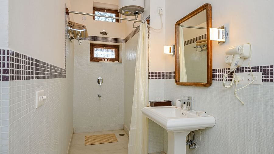 Bathroom with sink, mirror, shower curtain, windows, and wall-mounted hair dryer - Tijara Fort-Palace - 19th Century, Alwar.