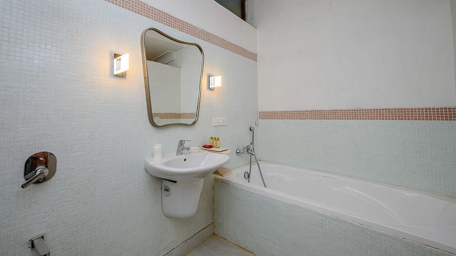 Bathroom with sink, mirror, wall lighting, bathtub, shower fixture, and tiled floor - Tijara Fort-Palace - 19th Century, Alwar.