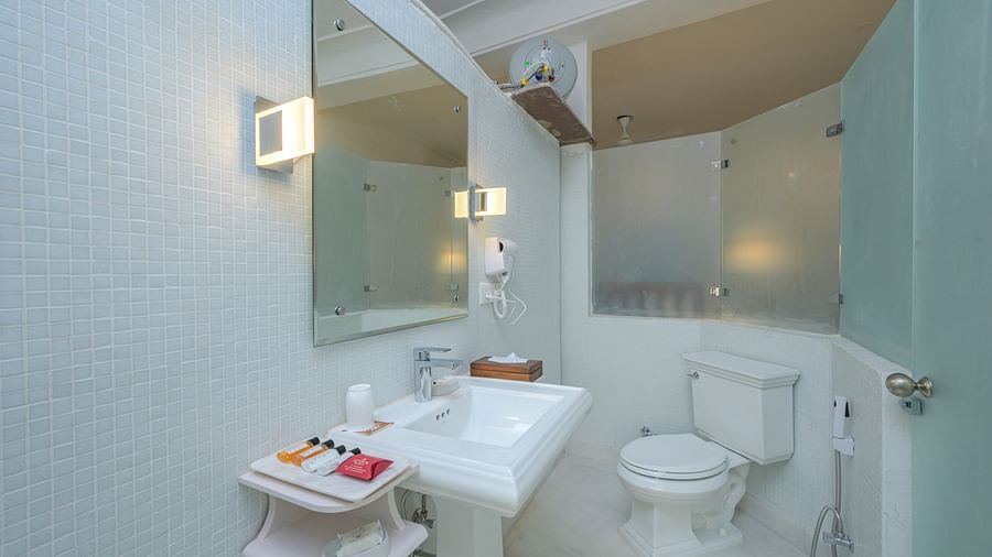 Interior of a bathroom at Tijara Fort-Palace - 19th Century, Alwar, featuring a sink, toilet, mirror, and shower stall.