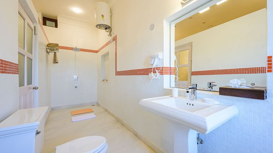 Bathroom with toilet, sink, mirror, shower, water heater, and tiled floor - Tijara Fort-Palace - 19th Century, Alwar.