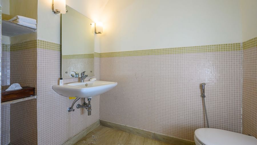 Bathroom with a sink, mirrors, lighting fixtures, shelves, and a toilet at Tijara Fort-Palace, Alwar.