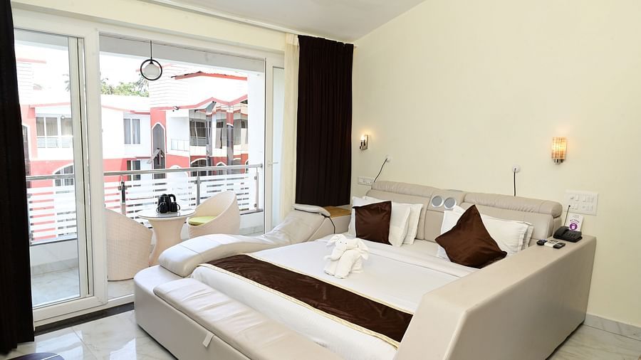 a modern bed with floor to ceiling glass sliding doors inside one of the rooms at VITS shanti solitaire, North Goa