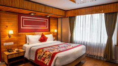 A well-furnished guest room with wooden interiors and a large window with a plushy bed at Mount Conifer Suites & Spa, Darjeeling