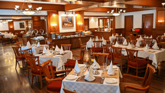 The sitting area at Silver Oak, one of the best restaurant in Kodaikanal , featuring wooden furnishings and white accents with a chandelier.