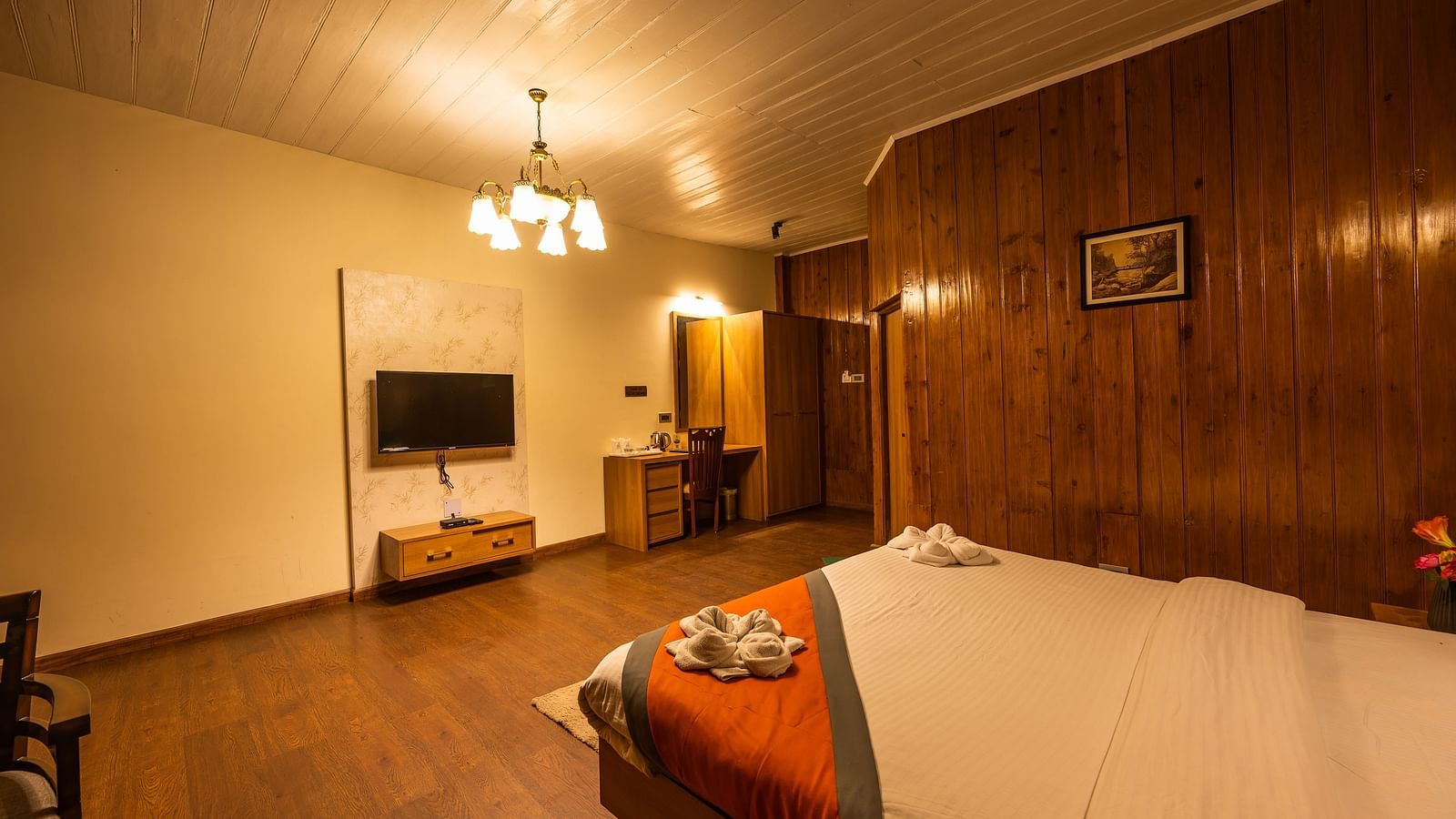 A top angle view of a spacious room with wooden furnished  comfy bed and the have flat screen TV at Arcadia Heritage Resort, Darjeeling