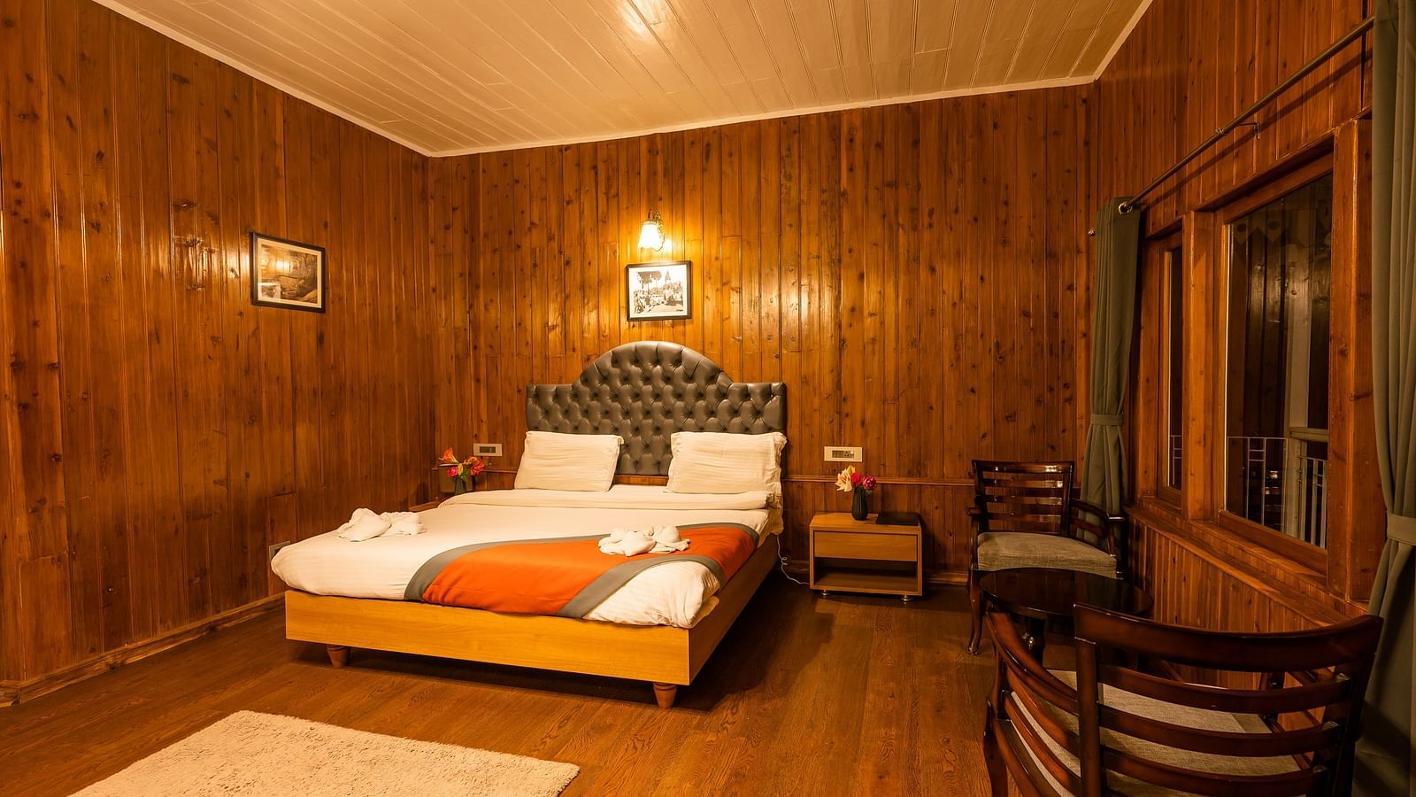 A spacious room with wooden furnished  comfy bed and the have bed side table and chair at Arcadia Heritage Resort, Darjeeling