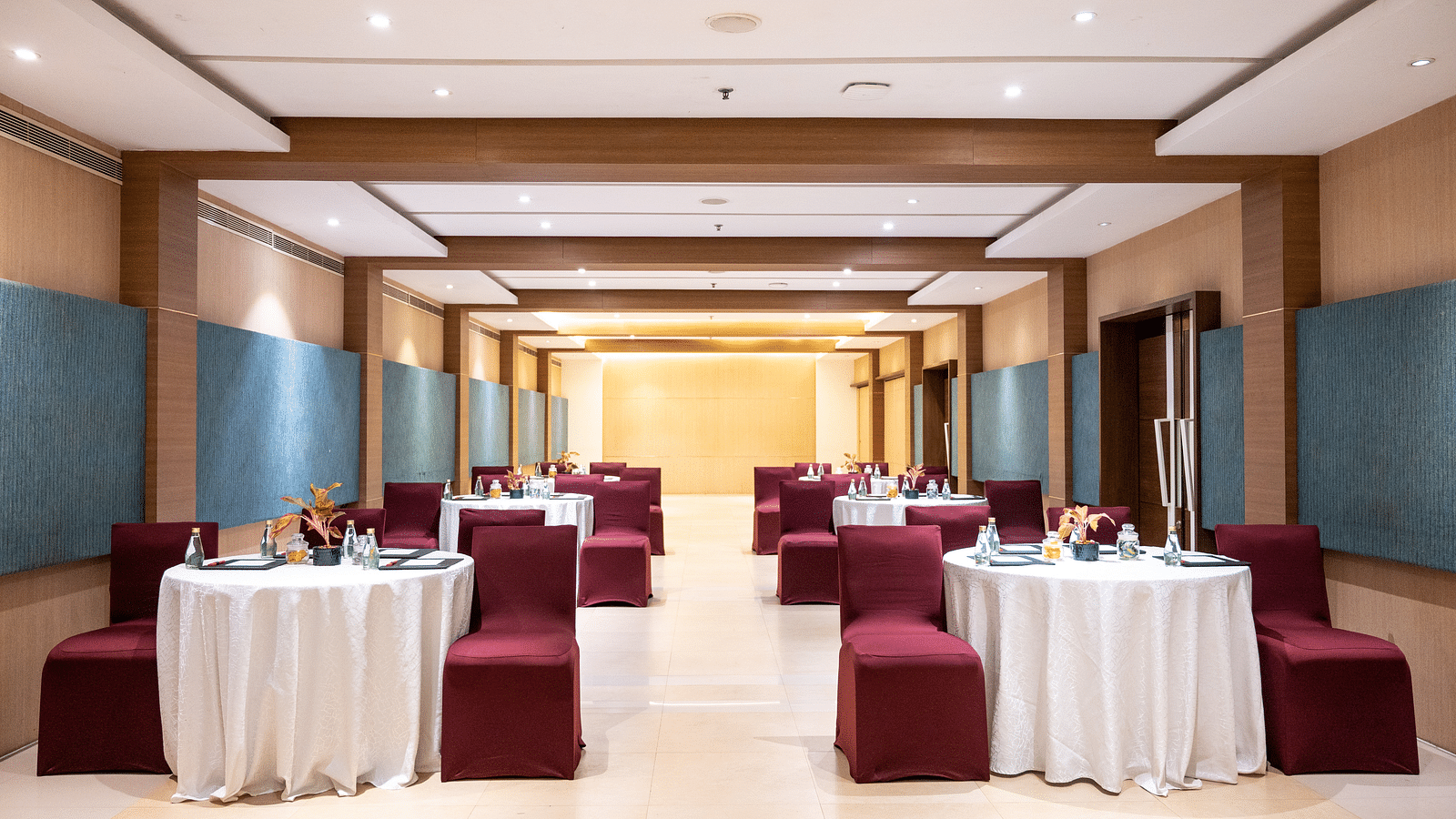 image of an event hall with tables and chairs at Grand Kakinada by GRT Hotels