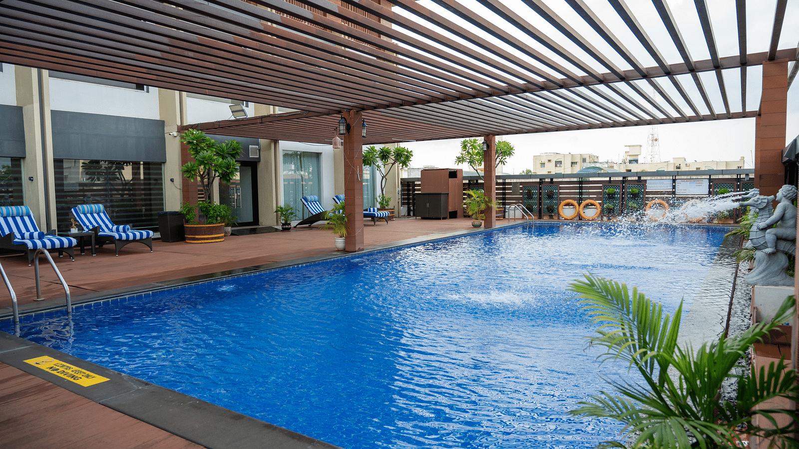 side view of the swimming pool with plants and sun loungers at Grand Kakinada by GRT Hotels