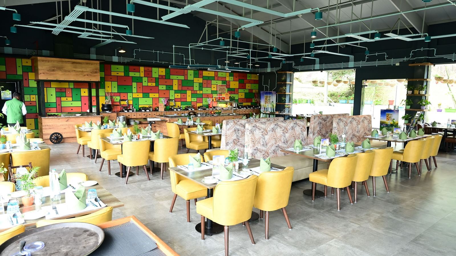 An image of a restaurant with seating arrangement, cutlery, and decorative items - GReaT trails Kodaikanal by GRT Hotels