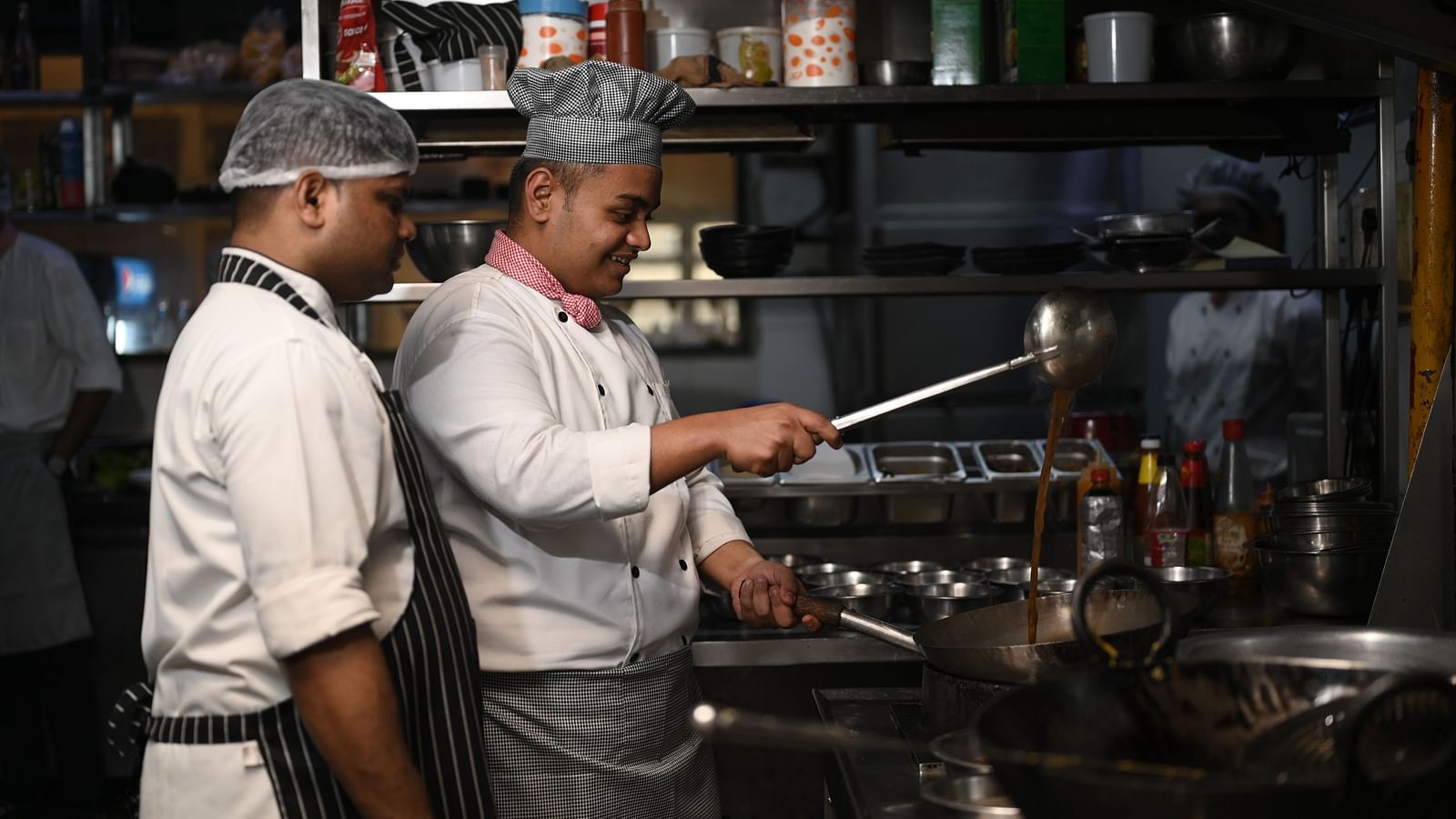 Two chefs preparing food in a professional kitchen - Kamats India