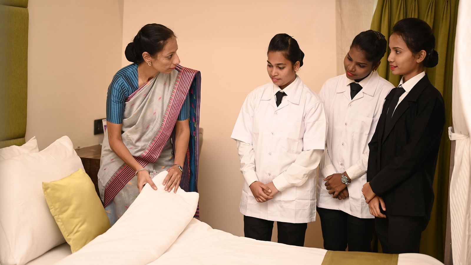 Trainer guiding staff on bed-making in a hotel room - Kamats India