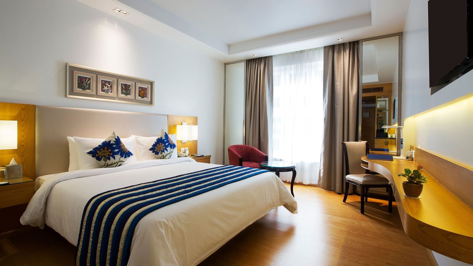 A bedroom with cosy and modern interiors featuring a double bed along with wooden flooring - Ramada by Wyndham, Ghaziabad, Vasundhara