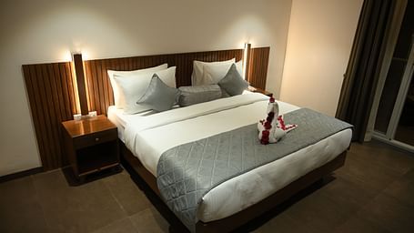 A doubled bed with a decorated towel at Deluxe room at  Mango Leaf Lake Resort, Pune