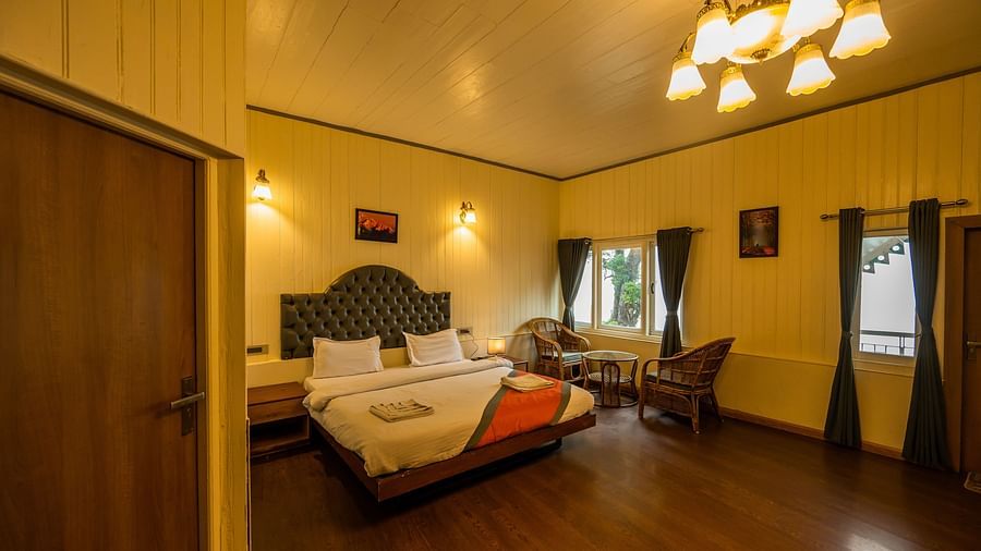 A room with beautiful interior with comfy bed, chair and bed side table at Arcadia Heritage Resort, Darjeeling 