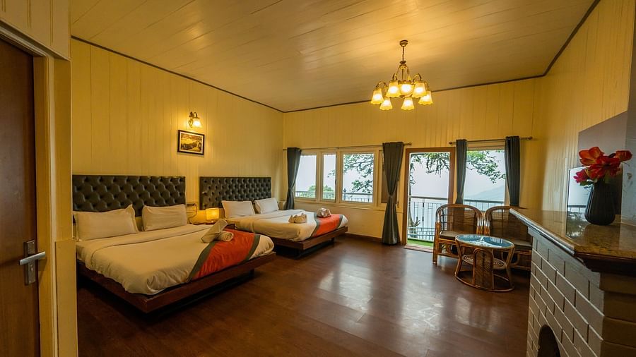 A spacious family room with 2 comfy beds, table, open window with a beautiful view  at Arcadia Heritage Resort, Darjeeling