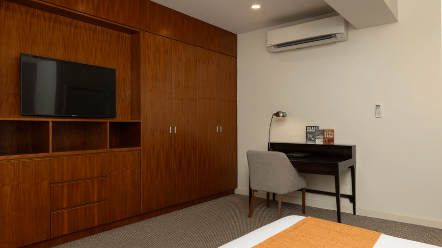 Penthouse bedroom at Central Mansions, Phnom Penh featuring a wall mounted television, work desk, and spacious interiors.
