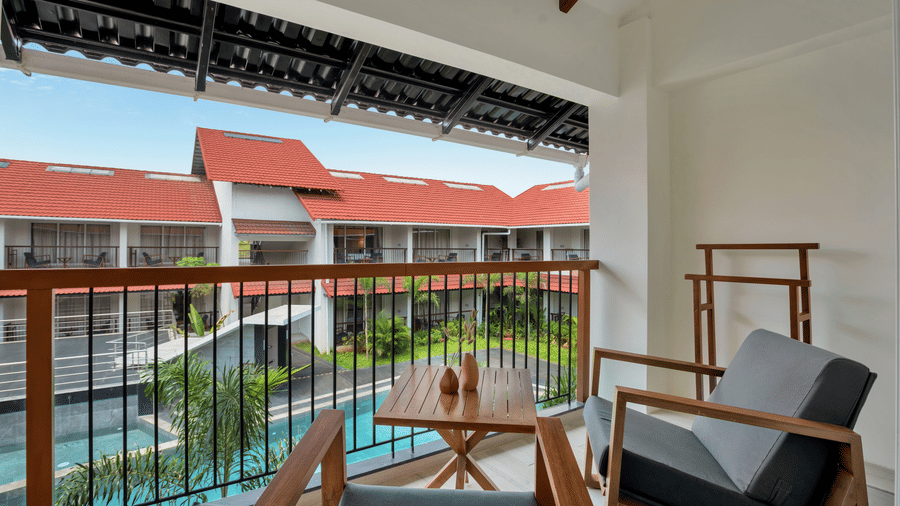 Balcony of Suite at Mango Hill, Velankanni with chairs and a table facing towards the resort courtyard and pool.