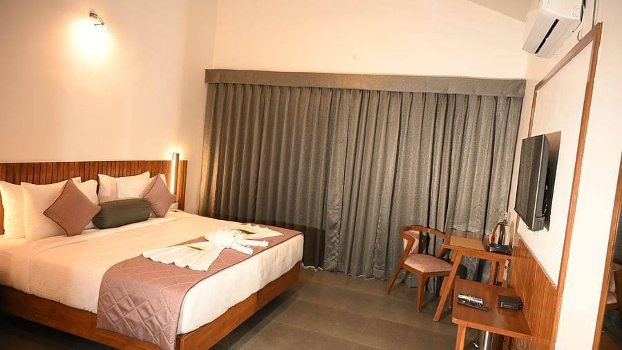 Wide view of a double bed and chairs and a table at the Deluxe Cottage at Mango Leaf Lake Resort, Pune