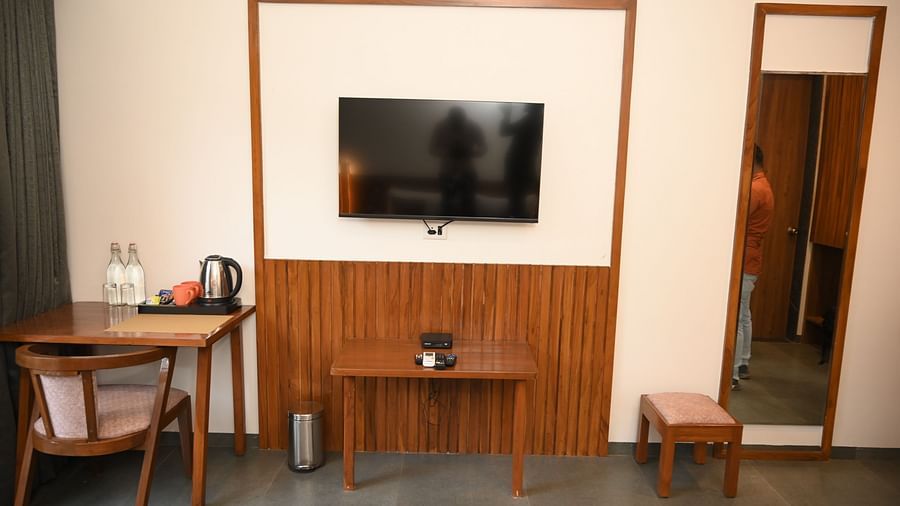 A television a table and a chair and a mirror at the Deluxe Cottage at Mango Leaf Lake Resort, Pune