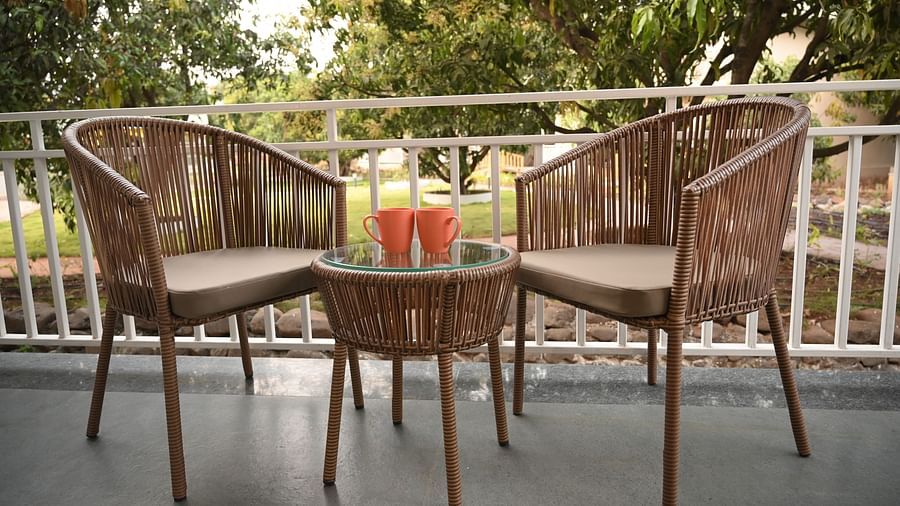 Two chairs with a small tea table with juice glasses kept on it outside  the Deluxe Cottage at Mango Leaf Lake Resort, Pune
