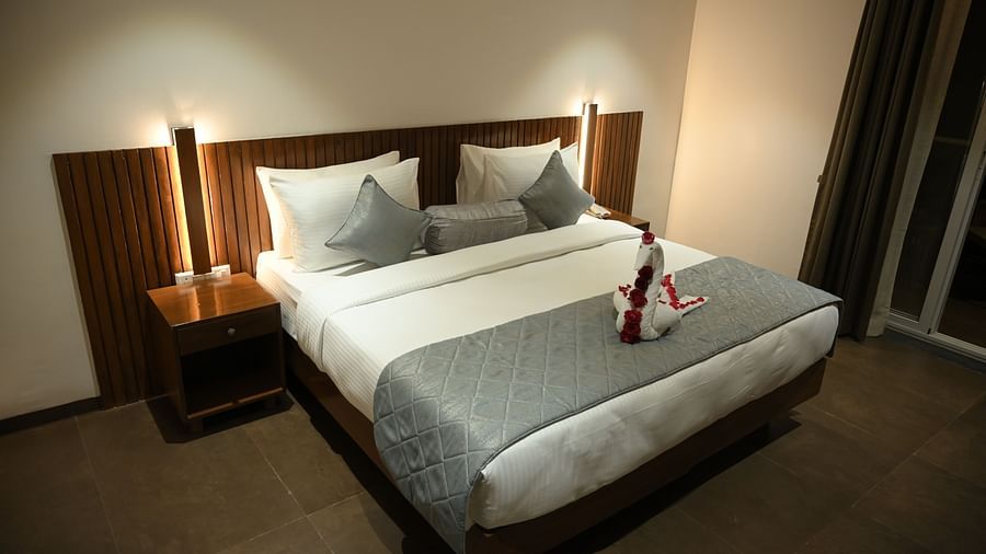 A doubled bed with a decorated towel at Deluxe room at  Mango Leaf Lake Resort, Pune