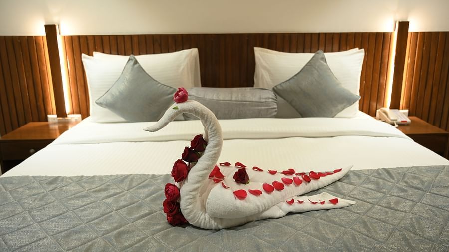 A towel shaped in the form of a swan decorated with flowers kept on a double bed at Deluxe room at  Mango Leaf Lake Resort, Pune